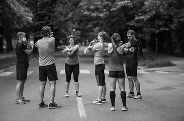 Image showing runners team warming up and stretching before morning training