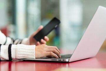 Image showing Woman working on laptop computer and cellphone