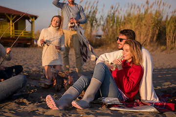 Image showing Couple enjoying with friends at sunset on the beach