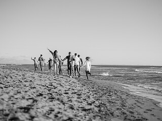 Image showing Group of friends running on beach during autumn day