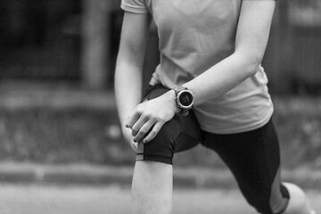 Image showing female runner warming up and stretching before morning training