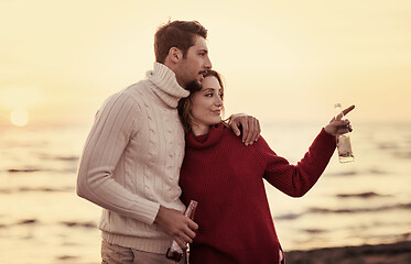 Image showing Couple hugging and drinking beer together at the beach