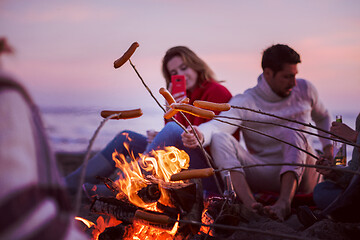 Image showing Group Of Young Friends Sitting By The Fire at beach