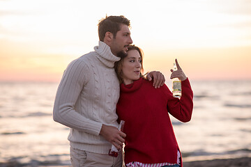 Image showing Couple hugging and drinking beer together at the beach