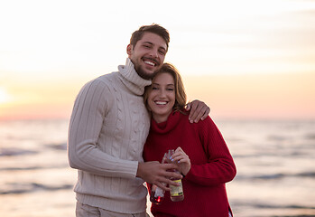 Image showing Couple hugging and drinking beer together at the beach