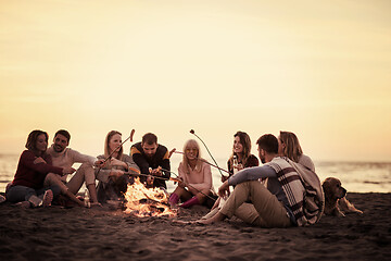 Image showing Group Of Young Friends Sitting By The Fire at beach