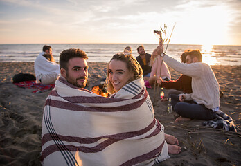 Image showing Couple enjoying with friends at sunset on the beach