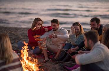 Image showing Group Of Young Friends Sitting By The Fire at beach