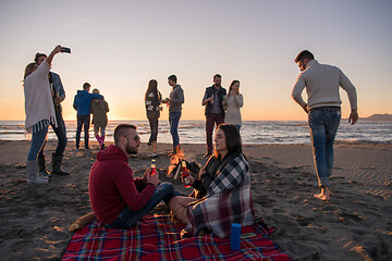 Image showing Couple enjoying with friends at sunset on the beach