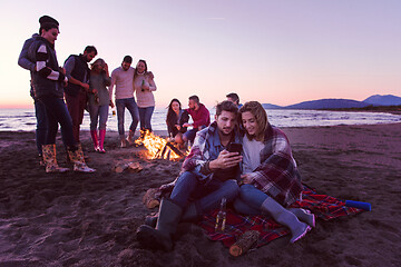 Image showing Couple enjoying bonfire with friends on beach