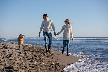 Image showing couple with dog having fun on beach on autmun day