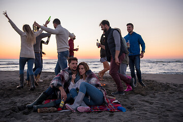 Image showing Couple enjoying with friends at sunset on the beach