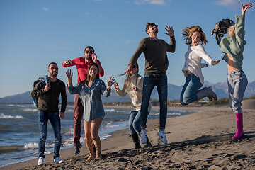 Image showing young friends jumping together at autumn beach