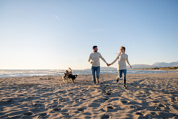 Image showing couple with dog having fun on beach on autmun day