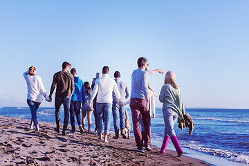 Image showing Group of friends running on beach during autumn day