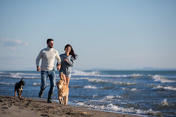 Image showing couple with dog having fun on beach on autmun day