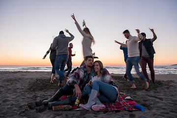 Image showing Couple enjoying with friends at sunset on the beach