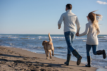 Image showing couple with dog having fun on beach on autmun day