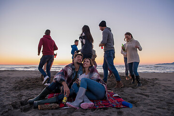 Image showing Couple enjoying with friends at sunset on the beach