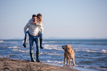 Image showing couple with dog having fun on beach on autmun day