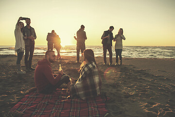 Image showing Couple enjoying with friends at sunset on the beach