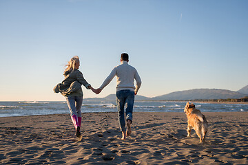 Image showing couple with dog having fun on beach on autmun day