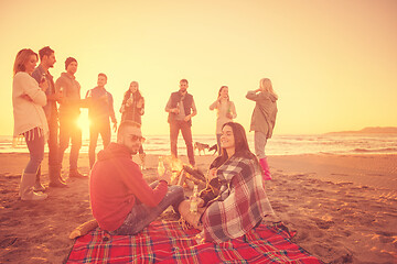 Image showing Couple enjoying with friends at sunset on the beach