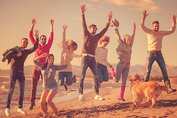 Image showing young friends jumping together at autumn beach
