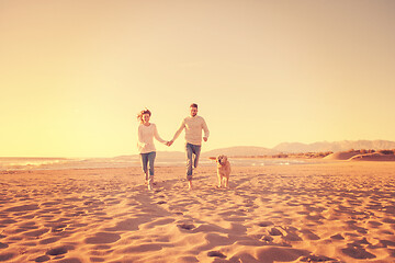 Image showing couple with dog having fun on beach on autmun day