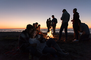 Image showing Couple enjoying bonfire with friends on beach