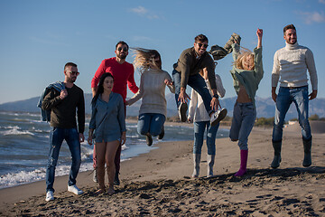 Image showing young friends jumping together at autumn beach