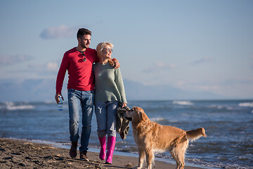 Image showing couple with dog having fun on beach on autmun day