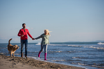 Image showing couple with dog having fun on beach on autmun day