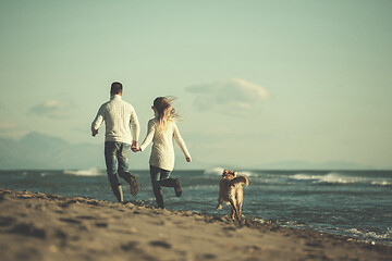 Image showing couple with dog having fun on beach on autmun day