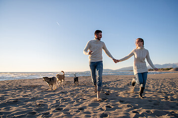 Image showing couple with dog having fun on beach on autmun day