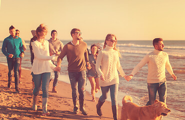 Image showing Group of friends running on beach during autumn day