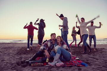 Image showing Couple enjoying with friends at sunset on the beach