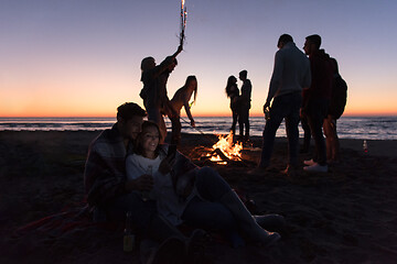 Image showing Couple enjoying bonfire with friends on beach