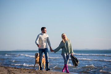 Image showing couple with dog having fun on beach on autmun day