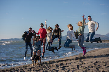 Image showing young friends jumping together at autumn beach