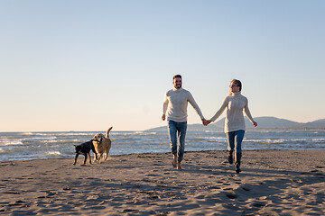 Image showing couple with dog having fun on beach on autmun day