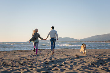 Image showing couple with dog having fun on beach on autmun day