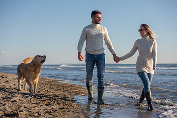 Image showing couple with dog having fun on beach on autmun day