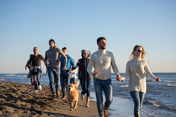 Image showing Group of friends running on beach during autumn day