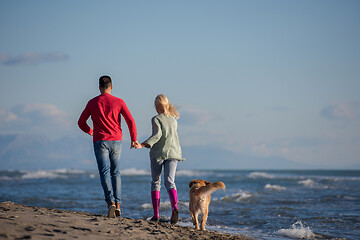 Image showing couple with dog having fun on beach on autmun day