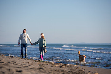 Image showing couple with dog having fun on beach on autmun day