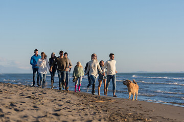 Image showing Group of friends running on beach during autumn day