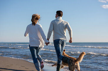 Image showing couple with dog having fun on beach on autmun day