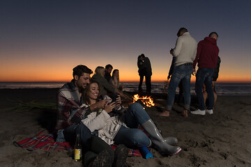 Image showing Couple enjoying bonfire with friends on beach