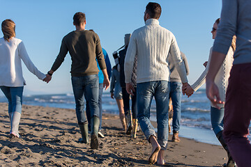 Image showing Group of friends running on beach during autumn day